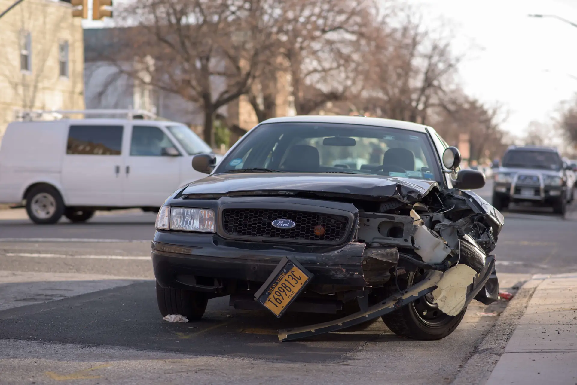Damaged black car on city street.
